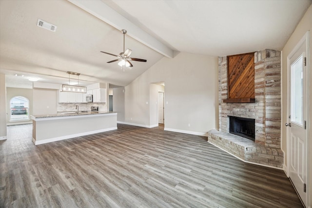 unfurnished living room with ceiling fan, a fireplace, wood finished floors, and visible vents