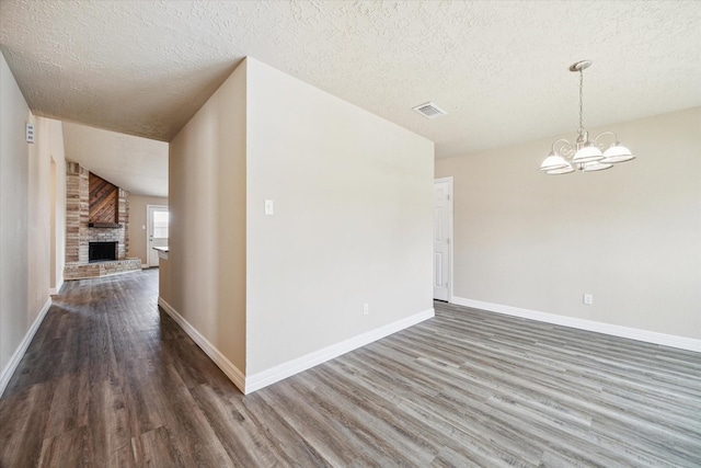 empty room featuring an inviting chandelier, baseboards, a textured ceiling, and wood finished floors