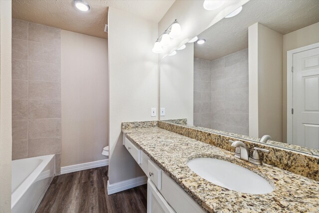 bathroom featuring vanity, wood finished floors, toilet, baseboards, and a textured ceiling