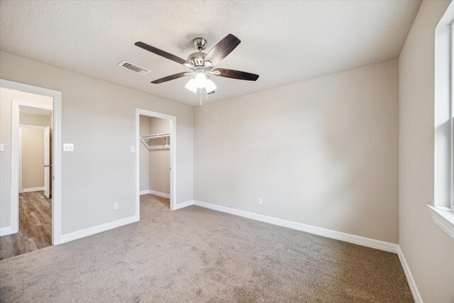unfurnished bedroom with visible vents, baseboards, carpet floors, and a spacious closet
