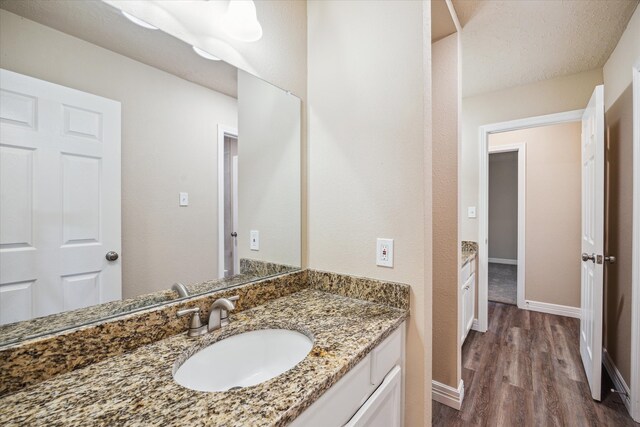 bathroom with baseboards, wood finished floors, and vanity