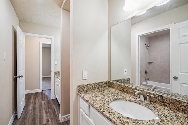 bathroom with shower / bathtub combination, baseboards, wood finished floors, and vanity