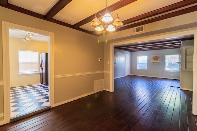 spare room with a chandelier, beamed ceiling, visible vents, and dark wood-style floors