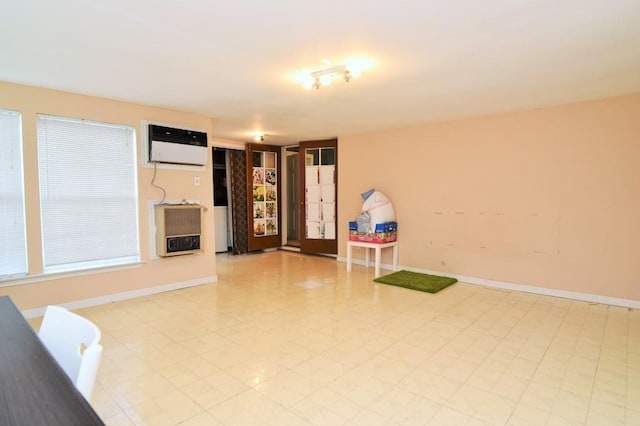 interior space with baseboards, heating unit, a wall mounted AC, and light floors