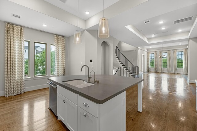 kitchen with dark countertops, a sink, baseboards, stainless steel dishwasher, and visible vents