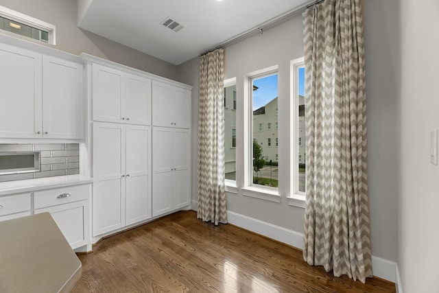 unfurnished dining area with baseboards, wood finished floors, and visible vents