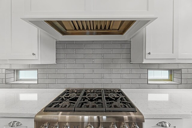 kitchen featuring white cabinets, light stone countertops, and tasteful backsplash