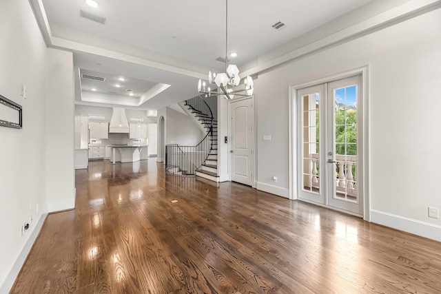 unfurnished dining area with baseboards, a tray ceiling, stairway, and dark wood-style floors