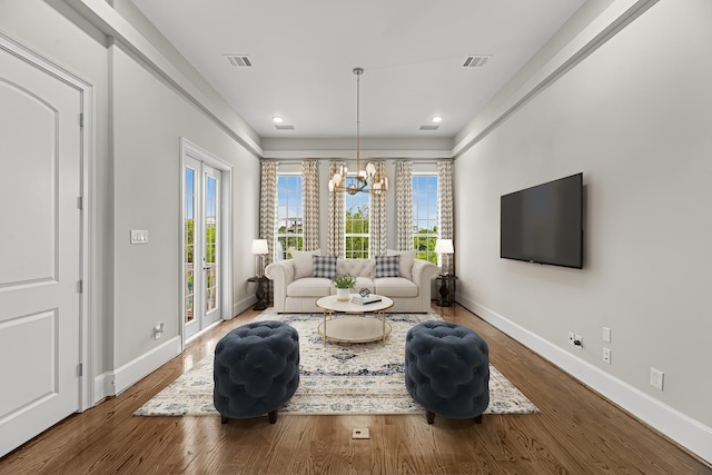 living room with an inviting chandelier, plenty of natural light, wood finished floors, and visible vents