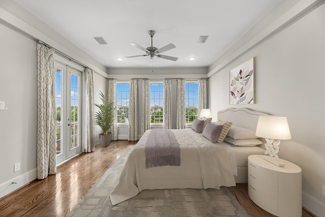 bedroom with baseboards, access to outside, wood finished floors, and visible vents