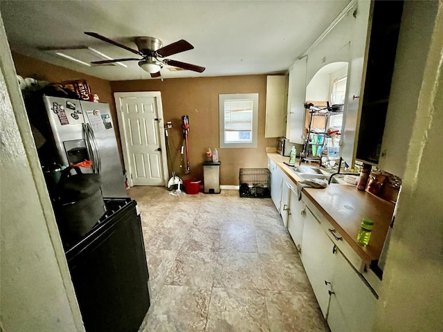 kitchen featuring stainless steel refrigerator with ice dispenser, a ceiling fan, and white cabinetry