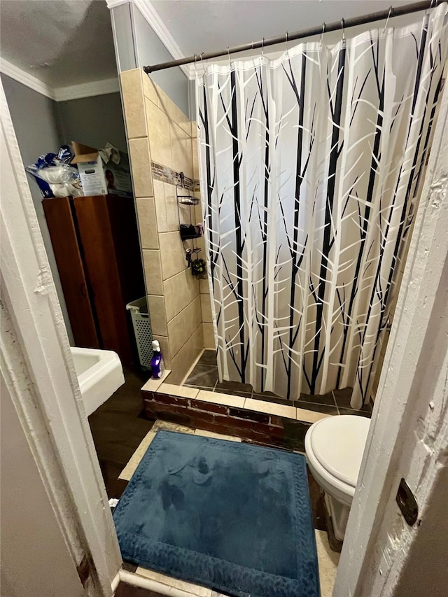bathroom with ornamental molding, a stall shower, toilet, and wood finished floors