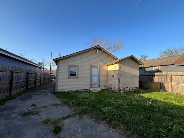 rear view of property featuring a lawn, fence, and entry steps