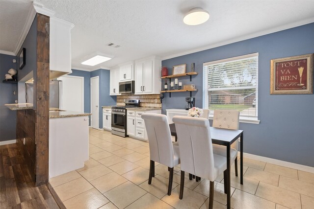 dining room with light tile patterned floors, baseboards, ornamental molding, and visible vents