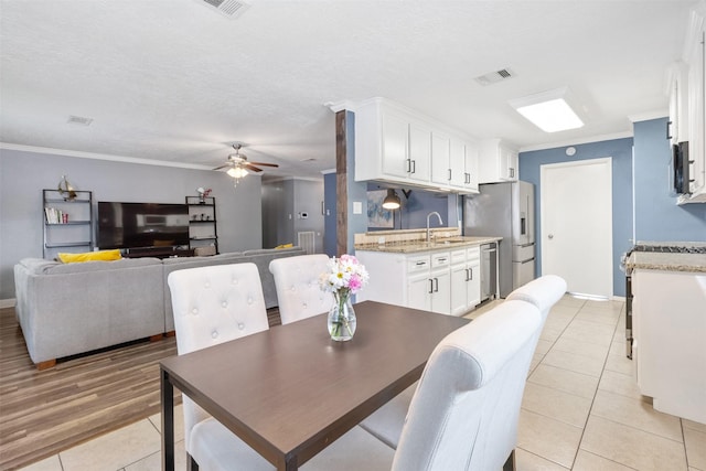 dining area with a ceiling fan, visible vents, crown molding, light tile patterned floors, and baseboards