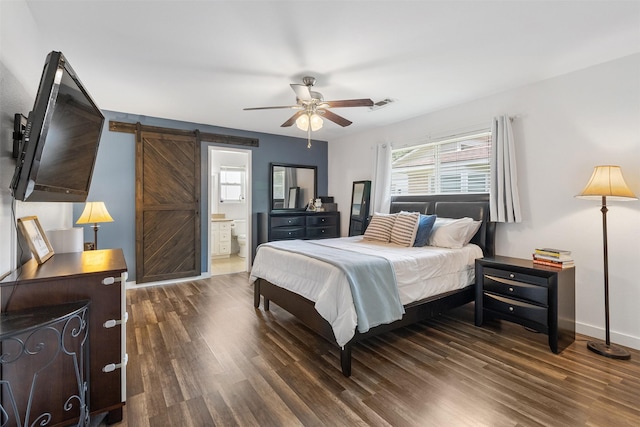 bedroom with visible vents, a barn door, wood finished floors, and ensuite bathroom