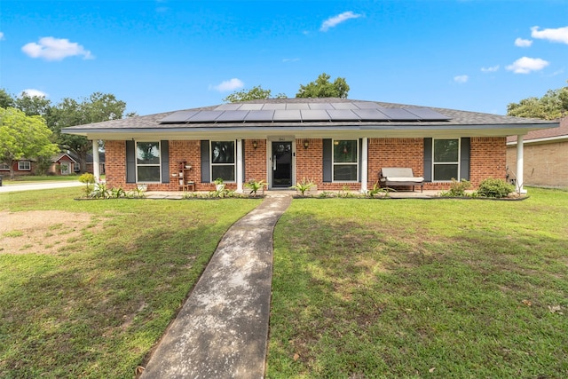 ranch-style house featuring covered porch, brick siding, and solar panels