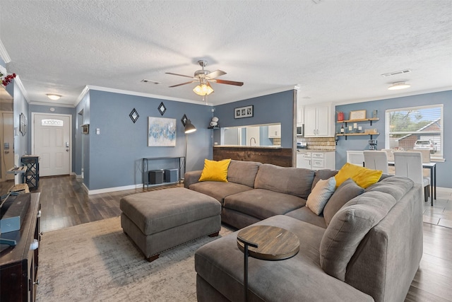 living room with visible vents, a ceiling fan, baseboards, and ornamental molding