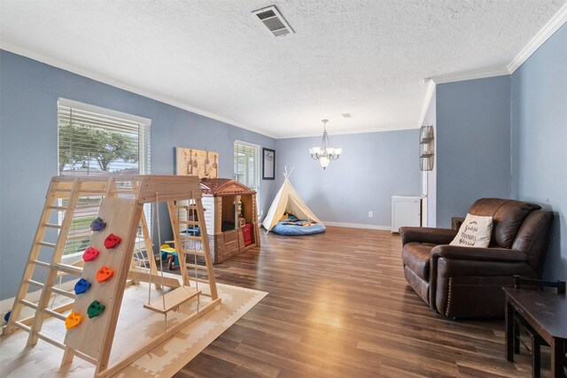 recreation room featuring visible vents, crown molding, an inviting chandelier, wood finished floors, and plenty of natural light