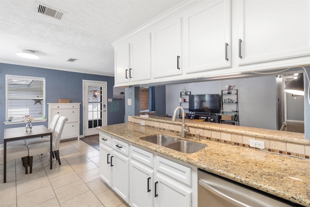 kitchen with visible vents, stainless steel dishwasher, a sink, light tile patterned floors, and white cabinets