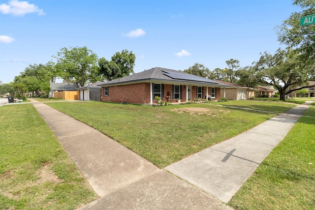 ranch-style house with covered porch, brick siding, solar panels, and a front lawn