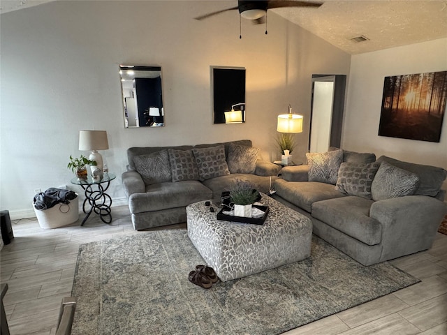 living area featuring ceiling fan, visible vents, baseboards, light wood finished floors, and lofted ceiling