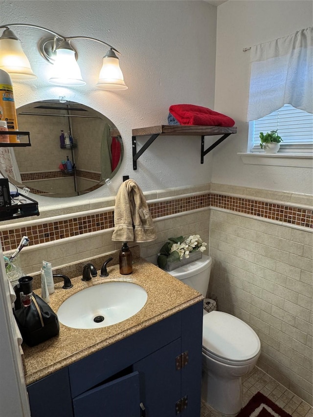 bathroom featuring vanity, wainscoting, toilet, tile walls, and tile patterned floors
