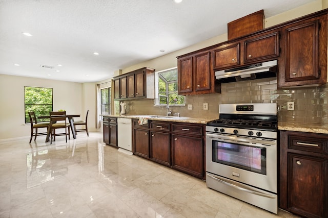 40206 Colfax Rd, Magnolia, TX 77354 - kitchen featuring stainless steel gas range, under cabinet range hood, white dishwasher, decorative backsplash, and plenty of natural light