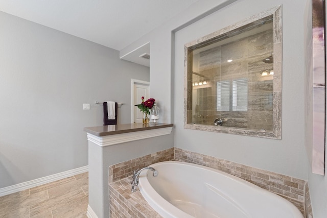 full bathroom with baseboards, a bath, and a tile shower