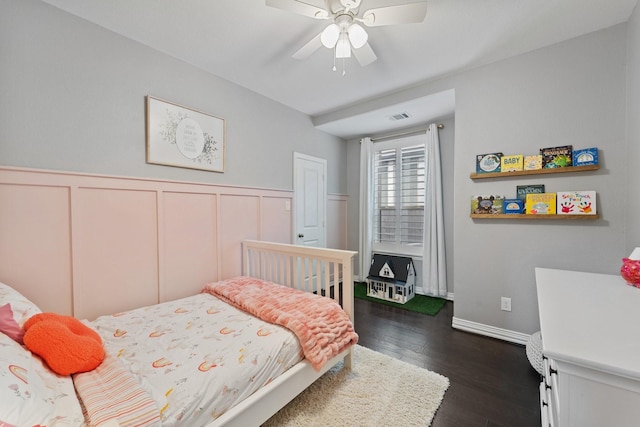 bedroom with visible vents, wainscoting, a decorative wall, and dark wood-style floors