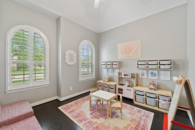 recreation room featuring dark wood-style flooring, baseboards, and a ceiling fan