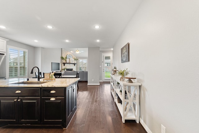 kitchen featuring a ceiling fan, light stone countertops, a sink, dark wood-style floors, and recessed lighting