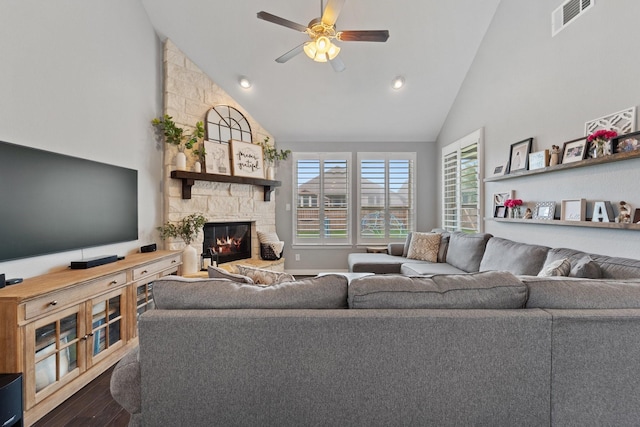 living room featuring visible vents, wood finished floors, a stone fireplace, ceiling fan, and high vaulted ceiling