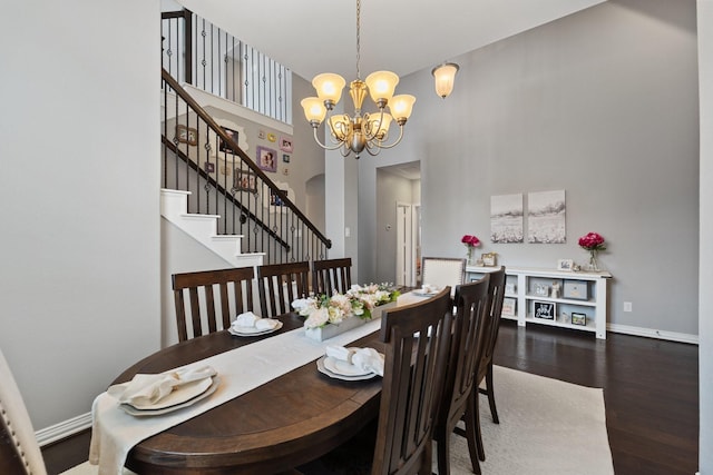 dining area featuring stairs, wood finished floors, baseboards, a high ceiling, and a notable chandelier