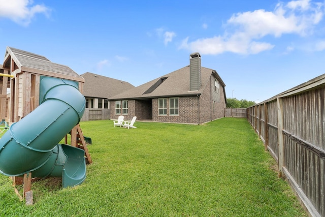 rear view of property with a lawn, brick siding, and a fenced backyard