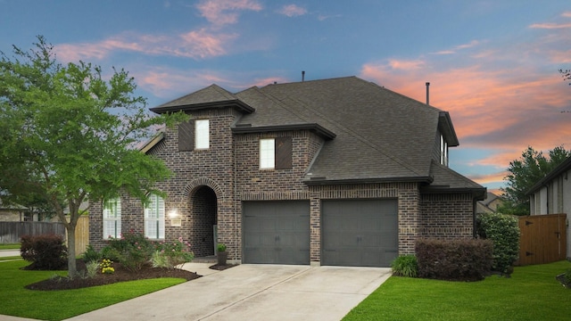 view of front of home with fence, a front yard, roof with shingles, brick siding, and concrete driveway