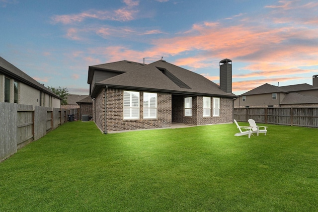 back of house featuring brick siding, a fenced backyard, and a lawn