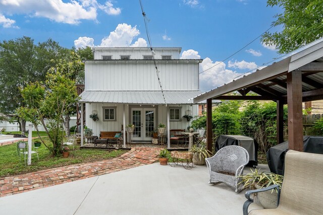 back of house with board and batten siding, french doors, metal roof, and a patio area