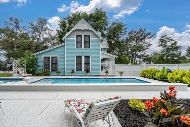 rear view of property with a fenced in pool, fence, and a patio area