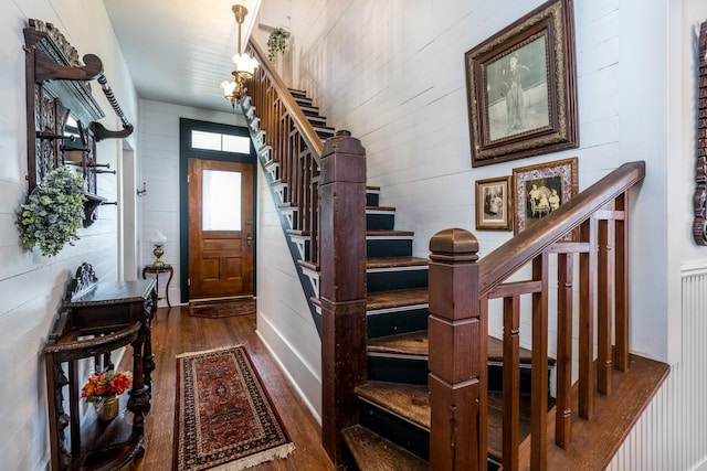 foyer featuring wood walls, wood finished floors, and stairway