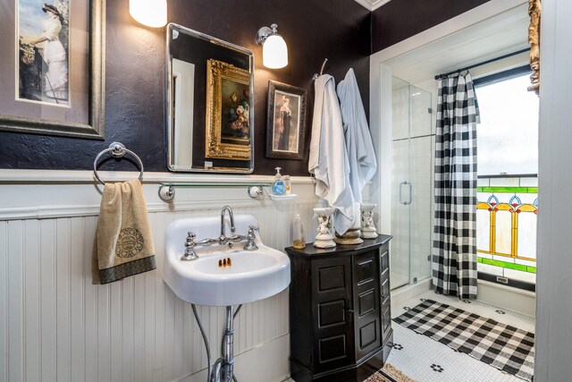 bathroom featuring tile patterned floors, wainscoting, and a stall shower