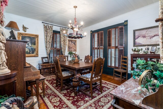 dining room with ornamental molding, wood finished floors, a notable chandelier, and a healthy amount of sunlight
