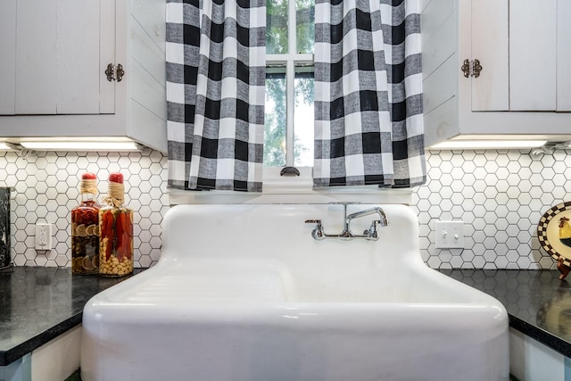 details with backsplash, dark countertops, a sink, and white cabinets