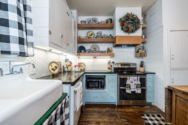 kitchen featuring appliances with stainless steel finishes, dark countertops, open shelves, a sink, and dark wood-type flooring