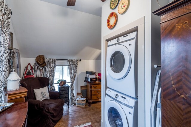 clothes washing area featuring a ceiling fan, laundry area, stacked washer / dryer, and wood finished floors
