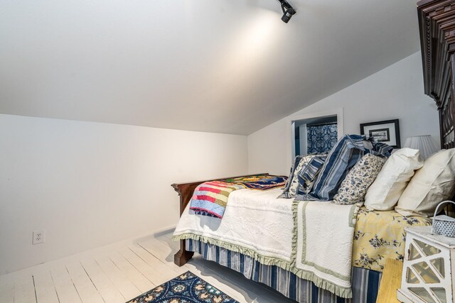 bedroom featuring wood finished floors and lofted ceiling