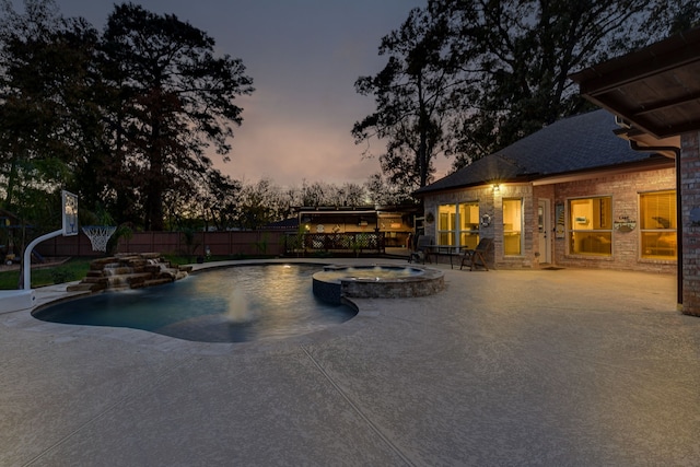 pool at dusk featuring a patio area, fence, and a pool with connected hot tub