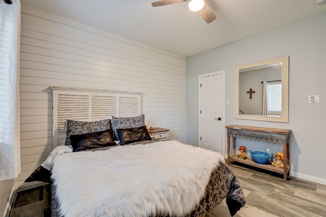 bedroom featuring baseboards, a ceiling fan, wood finished floors, and wood walls