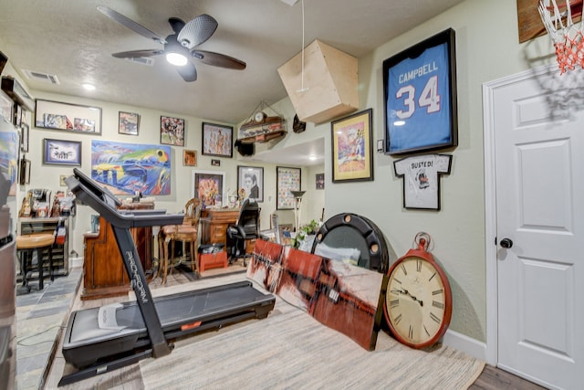 exercise area featuring baseboards, a ceiling fan, and visible vents