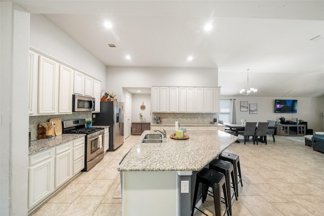 kitchen with decorative backsplash, a kitchen breakfast bar, a sink, an inviting chandelier, and stainless steel appliances